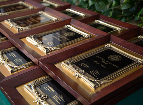 A pile of award plaques are stacked across a table