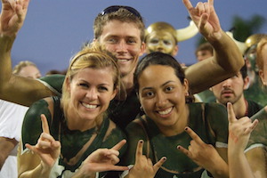 USF students at football game in green and gold paint.