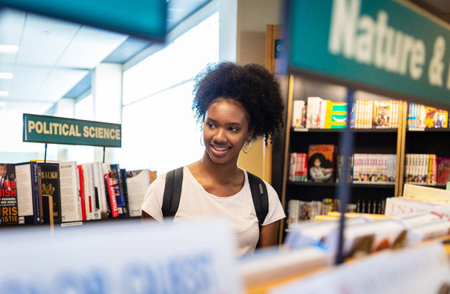 Young woman browsing bookshelves in Tampa campus library